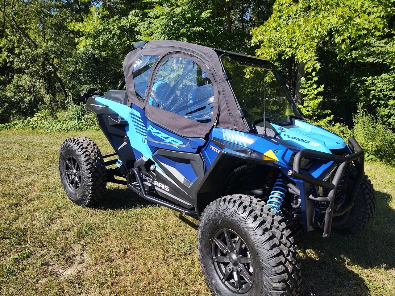 Wider front three-quarter view of the blue Polaris RZR Turbo S with Side X Side upper doors on a grassy field