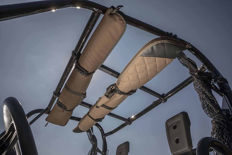 Two tan padded gun cases carried in the Kolpin overhead in-cab gun and bow rack under a UTV roll cage