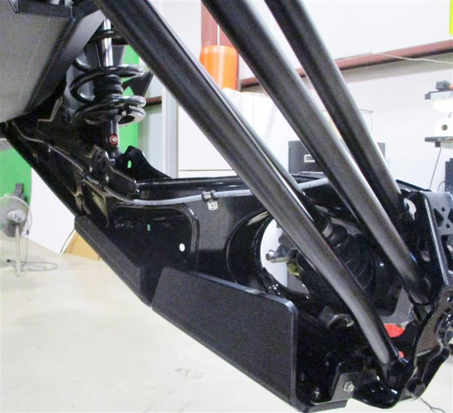 Trail Armor trailing arm guard installed on the Can-Am Maverick X3 rear suspension, viewed from behind the wheel well