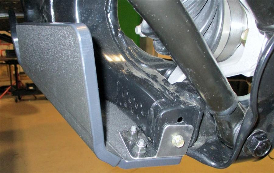 Close-up of the Trail Armor guard wrapping the rear end of a Maverick X3 trailing arm with hex bolt hardware