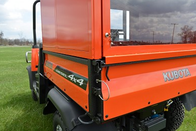 Close-up of the Wiedmann Bros bed cap glass door above the tailgate of the orange Kubota RTV