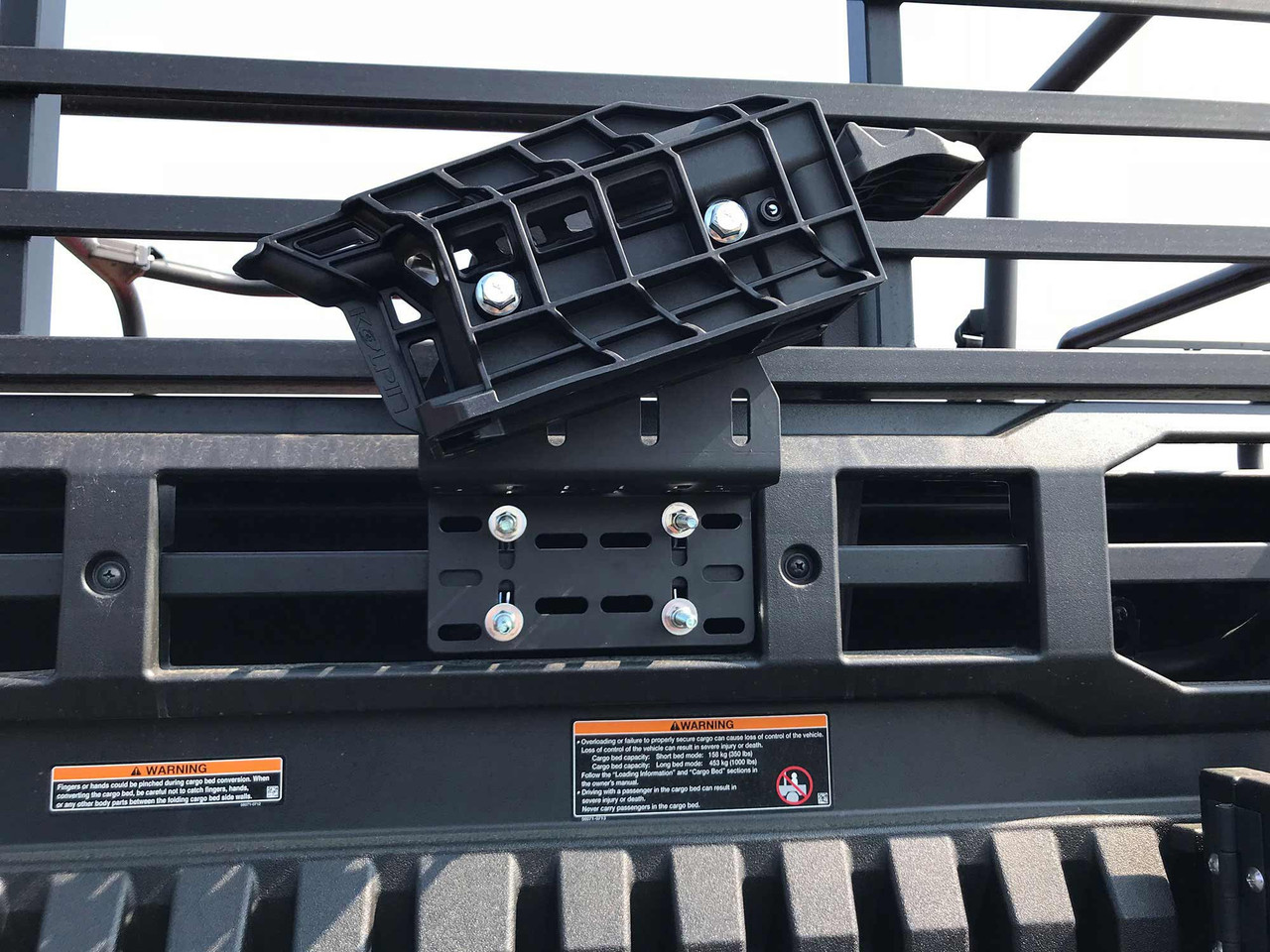 Kolpin Stronghold Auto-Latch mount bolted to a side-by-side cargo bed bulkhead, close-up