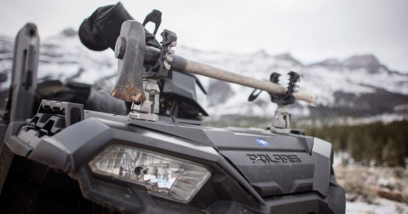 Kolpin Rhino Grip Pro holding a shovel and tool on the front rack of a Polaris Sportsman in snowy mountains