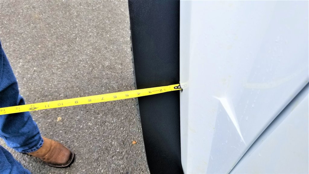 Close-up of a tape measure against the lower edge of the Trail Armor fender extension on a Yamaha Wolverine RMAX 2