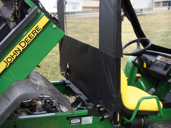 Side view of a John Deere Gator XUV with the 3 Star vinyl windshield and top, bed tilted up