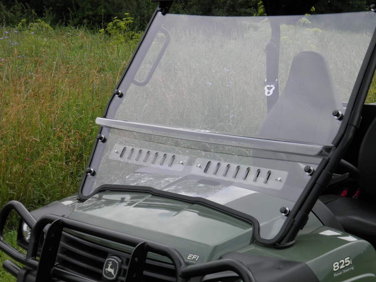 Angled front view of the 3 Star two-piece windshield with vent slots on a John Deere Gator XUV