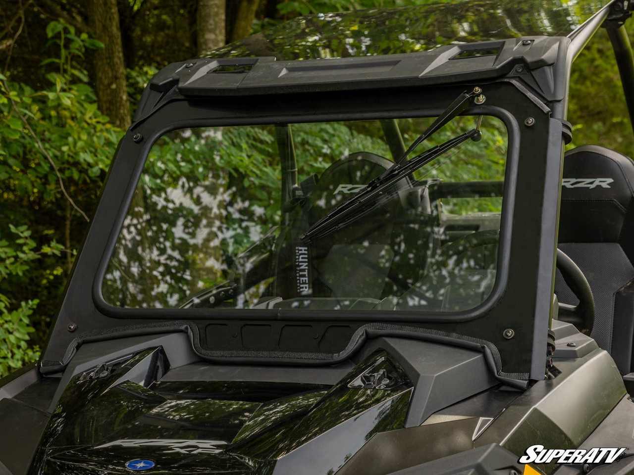 SuperATV black-framed glass windshield with wiper installed on a Polaris RZR XP Turbo, close front view in the woods
