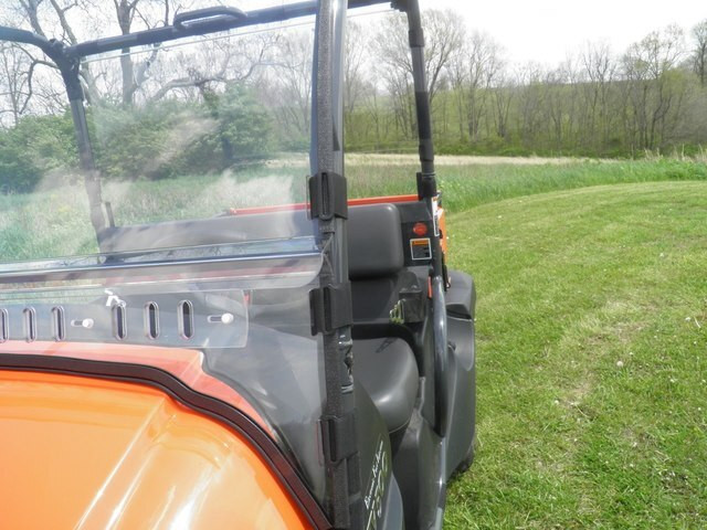 3 Star two-piece windshield installed on an orange Kubota utility vehicle, close-up from the side showing the hinge