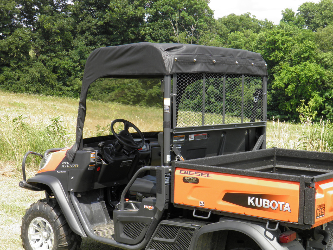 Rear three-quarter view of the orange Kubota RTV X1120 with the 3 Star vinyl top and windshield, cargo bed visible