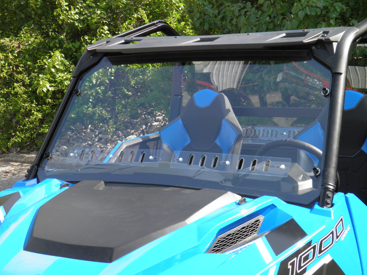 Front three-quarter view of the 3 Star one-piece windshield on a blue Polaris General 1000 under the roll cage