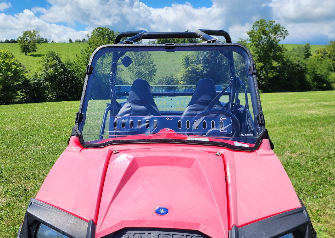 3 Star clear one-piece windshield on a red Polaris RZR, front close-up view outdoors