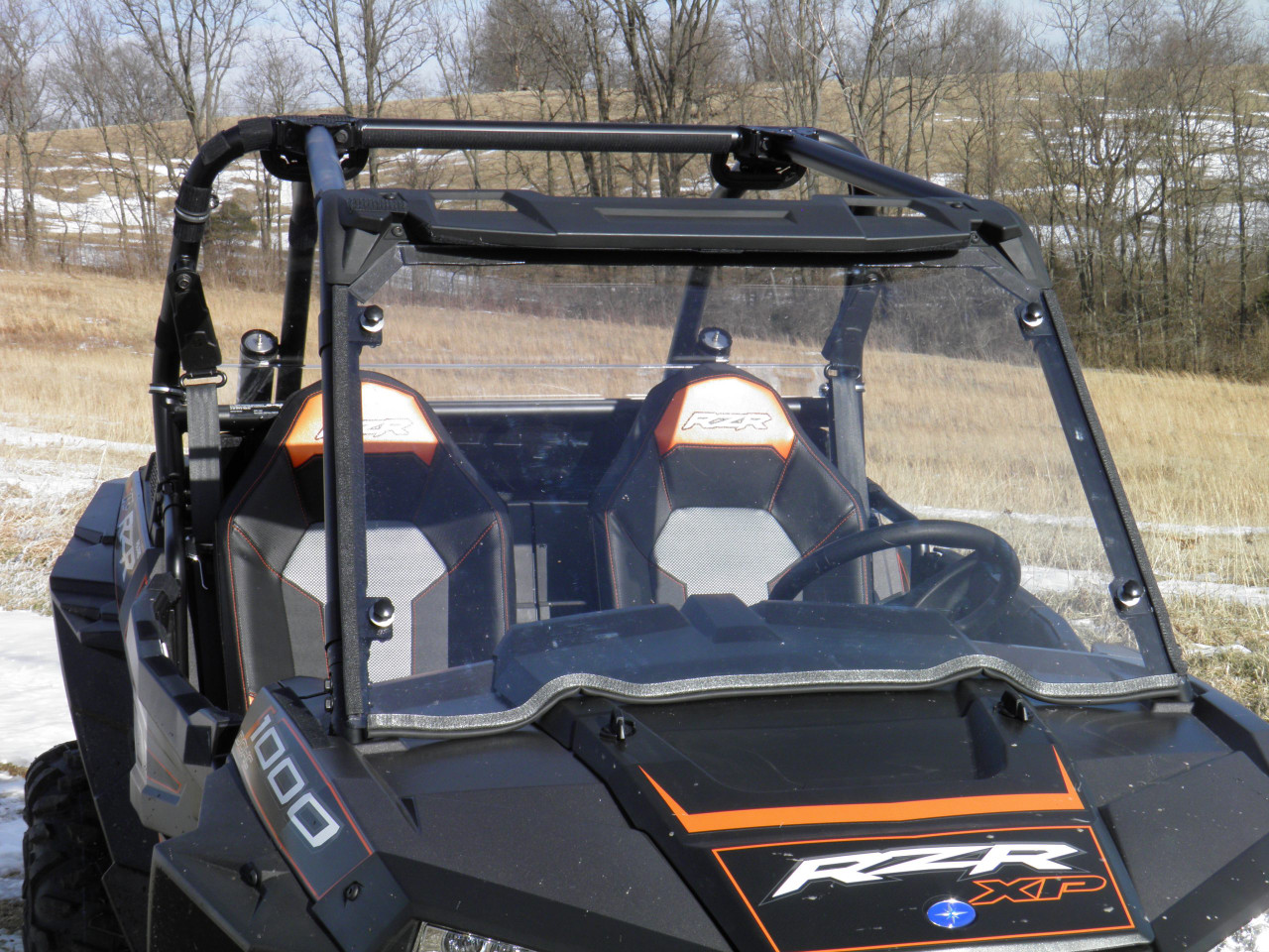 Angled front view of the 3 Star one-piece windshield on a black Polaris RZR XP1000 showing the cage clamps