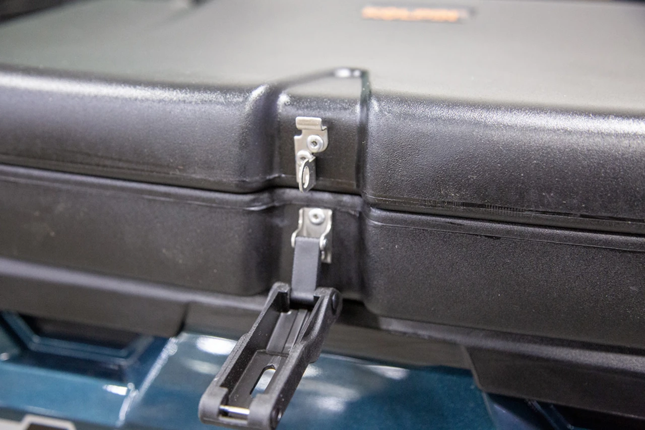 Close-up of the Kolpin saddle storage box front latch flipped open, mounted in a Polaris Ranger bed