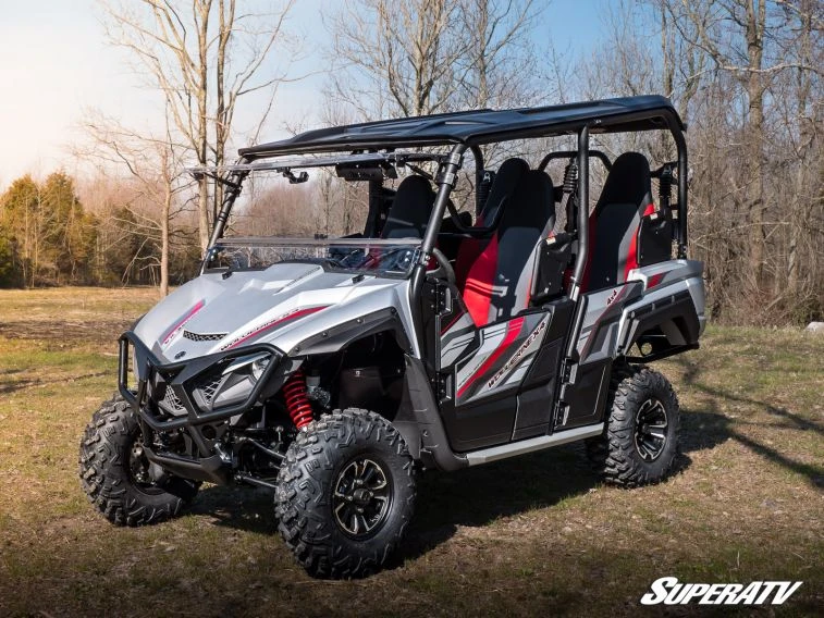 SuperATV flip windshield installed on a silver and red Yamaha Wolverine X4, front three-quarter view in a field
