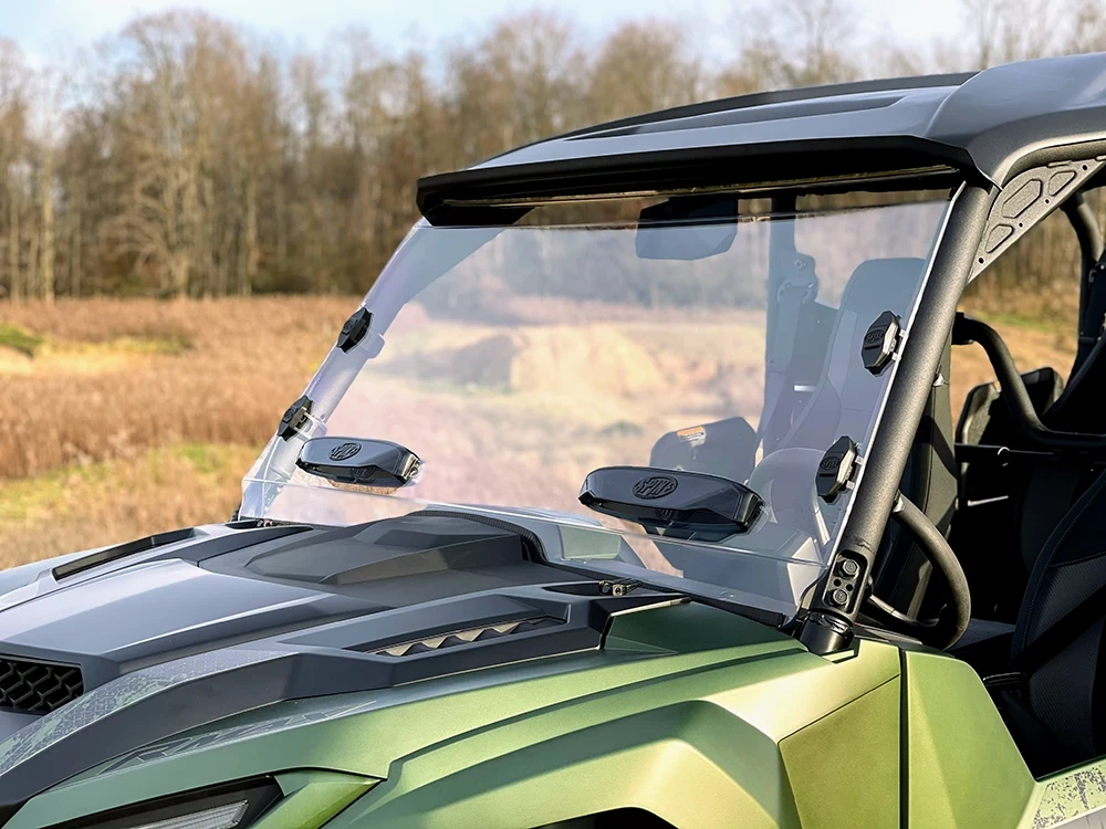 Spike windshield for Yamaha Wolverine RMAX: vented windshield on a green UTV, front corner close-up outdoors