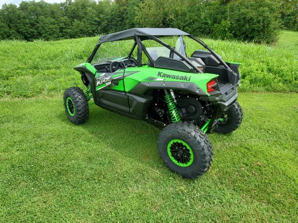 Rear corner view of a green Kawasaki KRX with the 3 Star black soft top on a grassy hill
