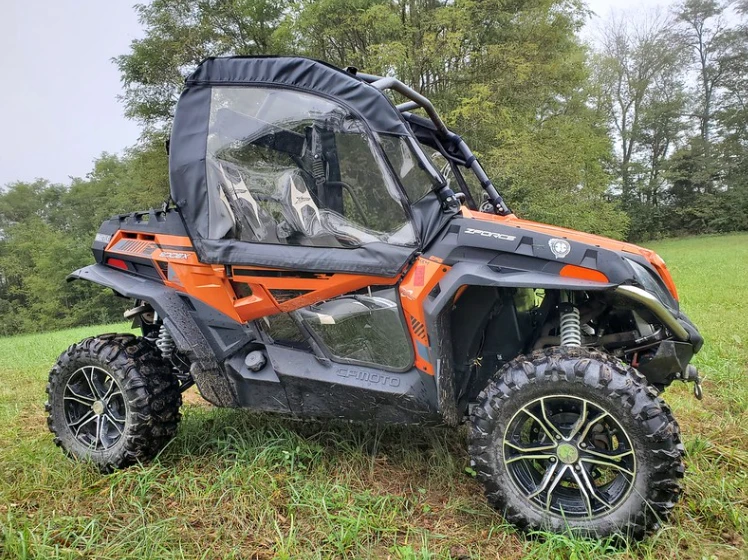 Front three-quarter driver side view of an orange CFMoto ZForce with 3 Star soft doors and front tire