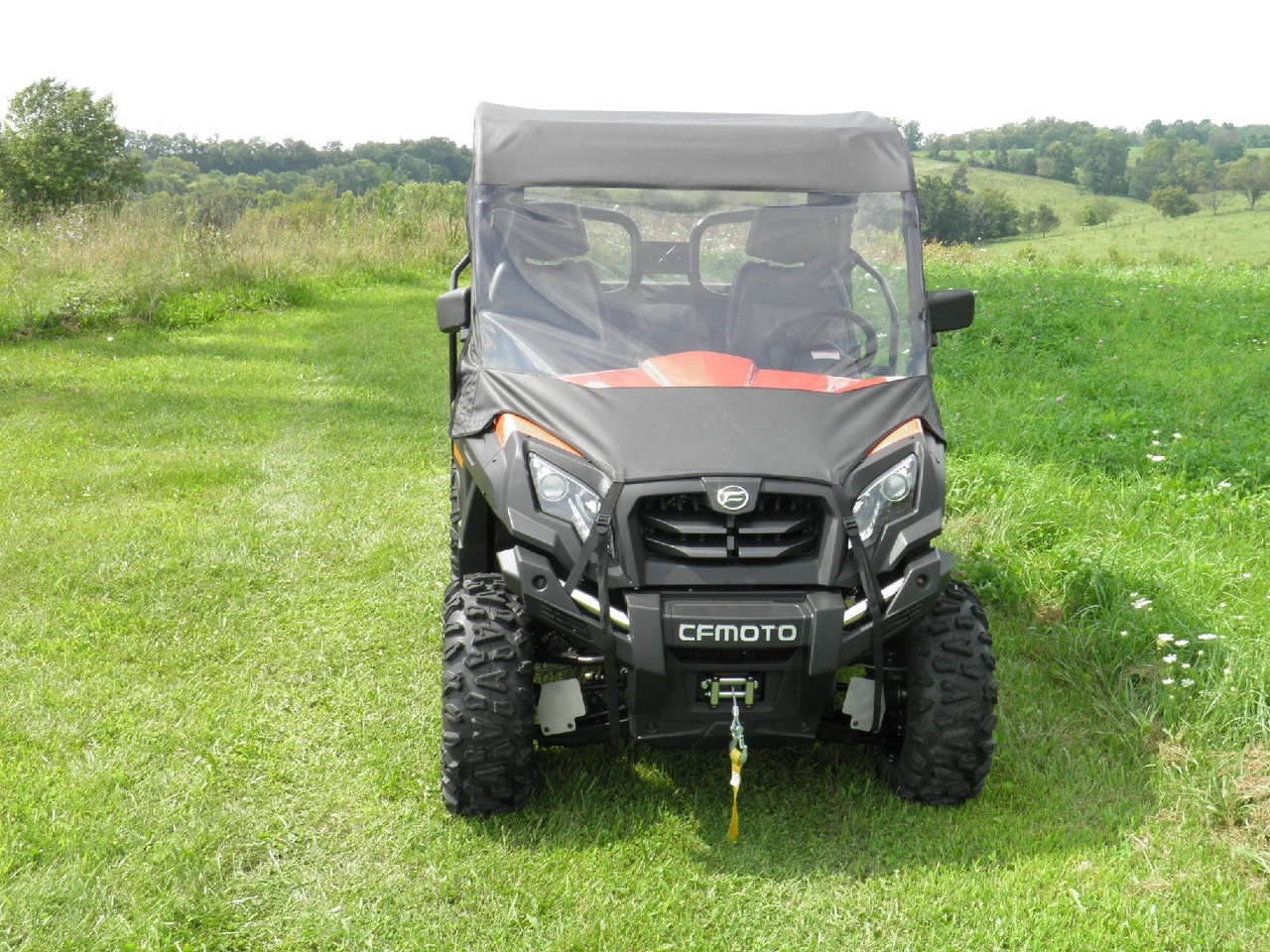 Straight front view of a CF Moto UForce 500/800 with the 3 Star vinyl windshield and grey top installed in tall grass