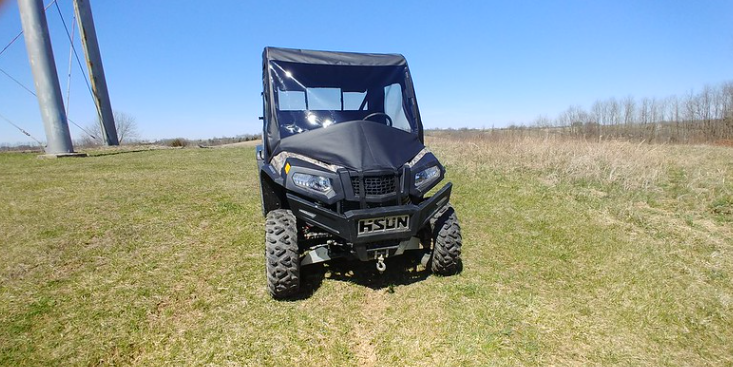 Distant front view of a camo Hisun Sector 550/750 wearing the 3 Star full cab enclosure in an open field