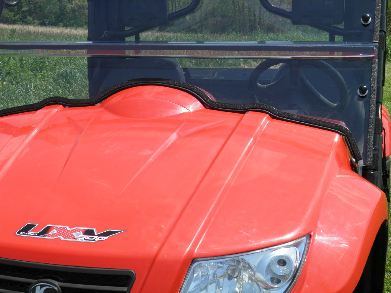 Close-up of the 3 Star windshield lower edge seal where it meets the red Kymco 700 hood
