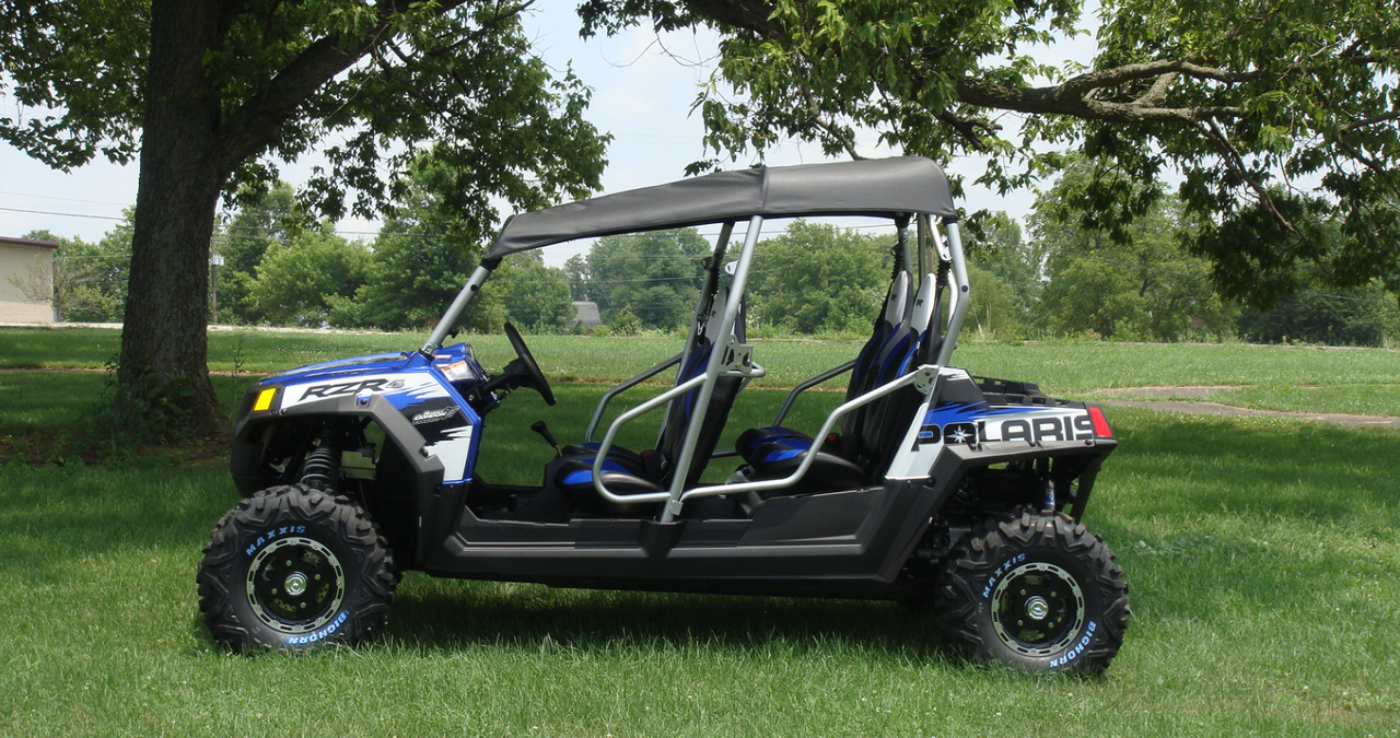 Side view of a blue Polaris RZR 4 with the 3 Star black soft top parked under a tree