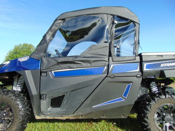 Close-up side view of the 3 Star soft door with clear window on a blue Arctic Cat Stampede