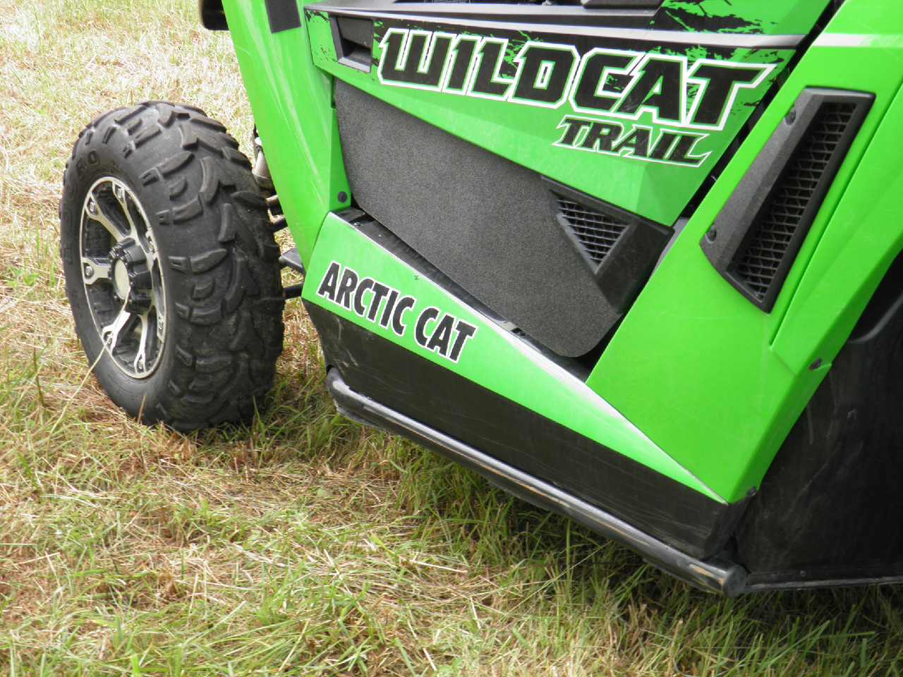 Passenger side view of the 3 Star ABS lower door insert on a green Arctic Cat Wildcat Trail with rear tire