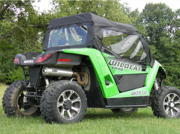 Green Arctic Cat Wildcat Trail with 3 Star full cab enclosure, driver side rear three-quarter view showing the rear window