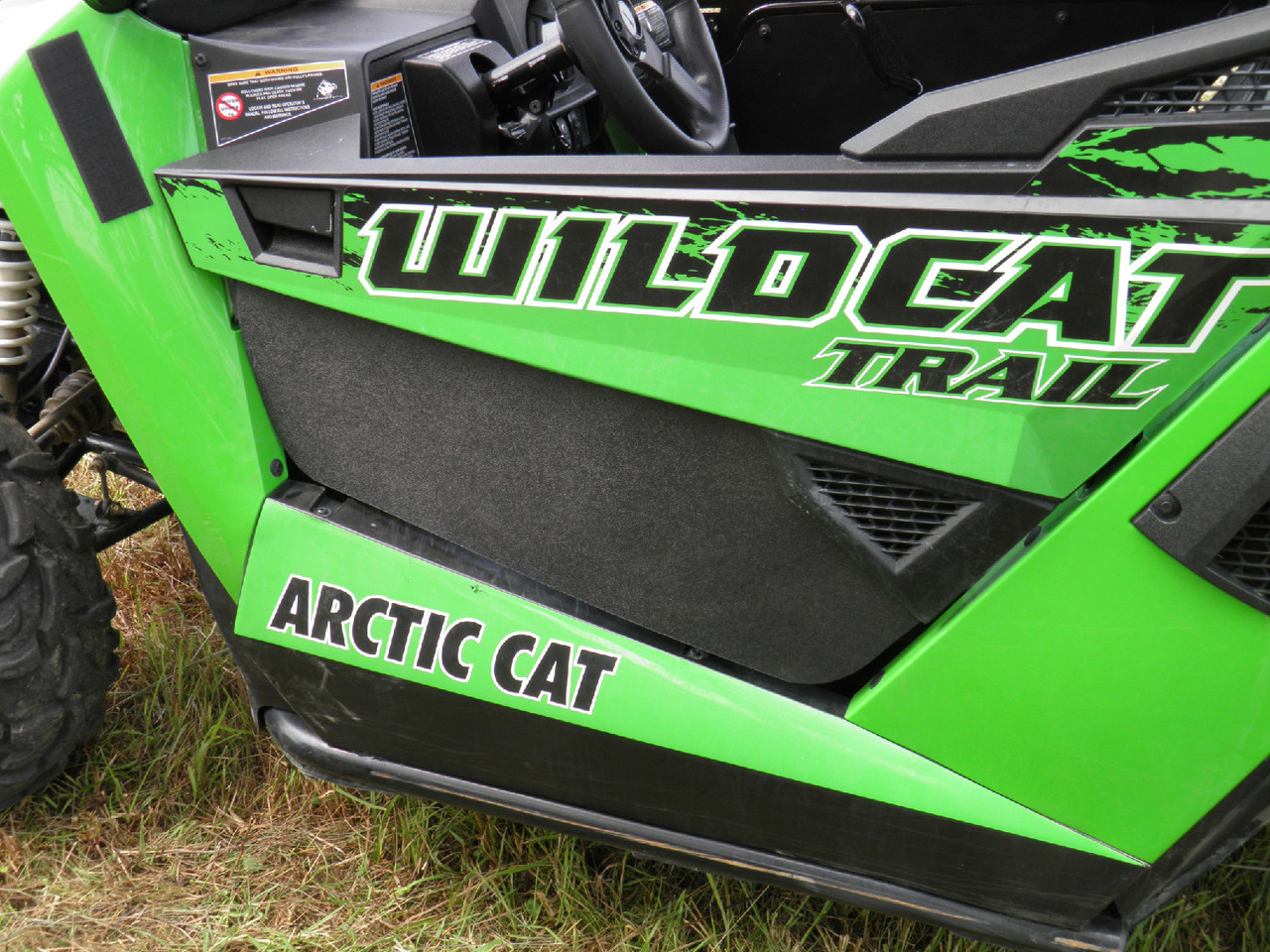 Close-up of the black 3 Star lower door insert fitted to the driver side of a green Arctic Cat Wildcat Trail