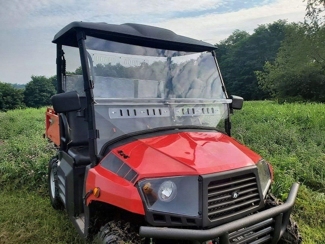3 Star 2-piece windshield installed on a red Coleman 400 side-by-side, front three-quarter view in tall grass