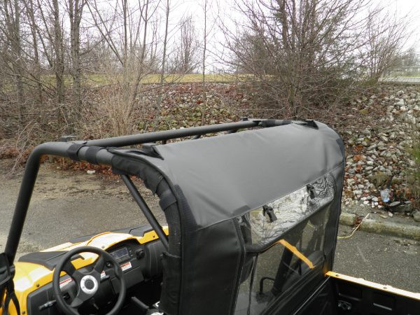 3 Star vinyl rear window with clear panel seen from inside the cab of a yellow Cub Cadet Challenger, strap and zipper visible