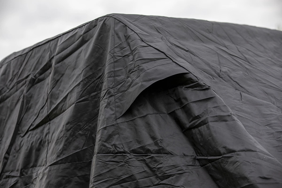 Close-up of the peaked top and seams of the Kolpin black UTV cover fitted over a machine outdoors