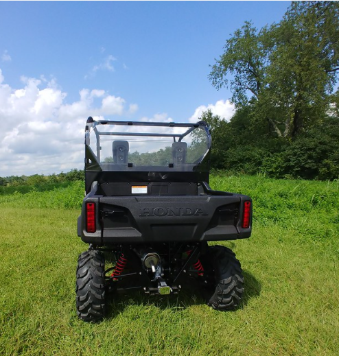 3 Star Lexan rear window on the cage of a black Honda Pioneer 700, straight rear view over the tailgate in a field