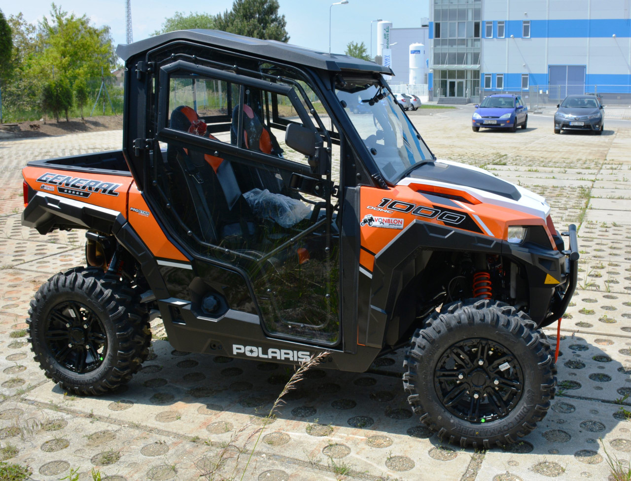 Passenger side view of a four-seat orange Polaris General 1000 with the Hard Cabs full enclosure and doors
