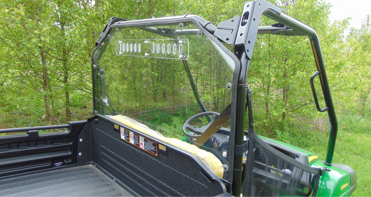 Angled view from the bed of the 3 Star Lexan back panel behind the seats of a green John Deere Gator