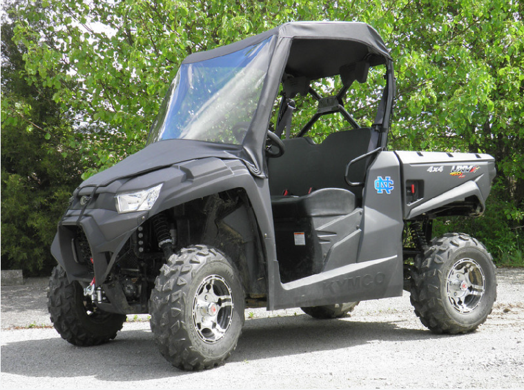 Driver side front view of a black Kymco UXV 700 with the 3 Star vinyl windshield and top on a gravel lot