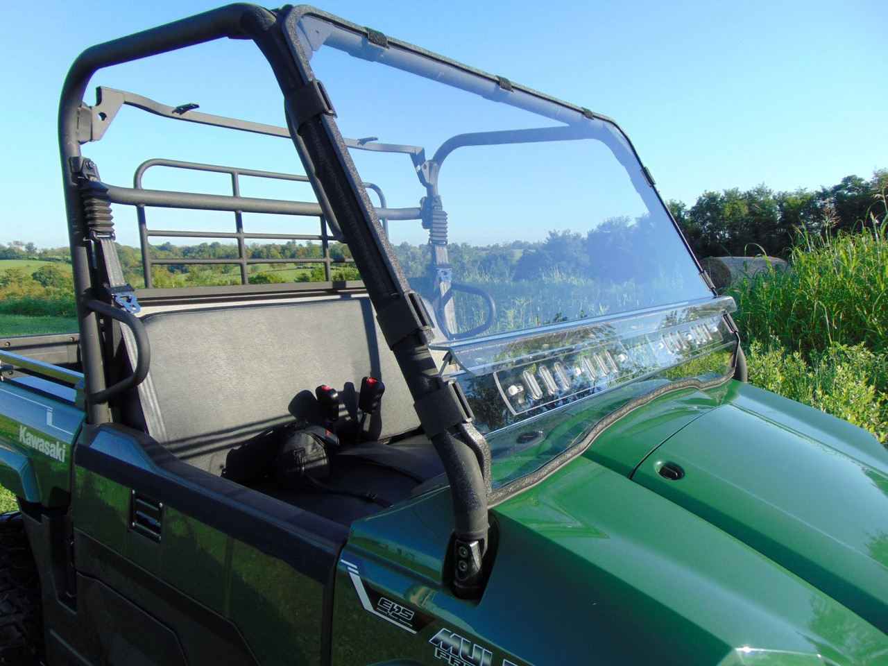 Side angle of the 3 Star 2-piece windshield on a green Kawasaki Mule ProMX showing the cage clamps
