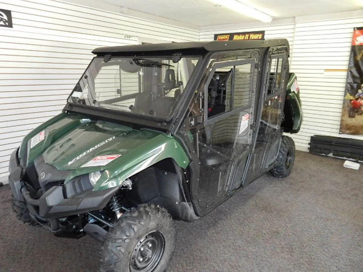 Hard Cabs hard cab enclosure on a green Yamaha Viking VI, glass doors and windows, front 3/4 view in a showroom