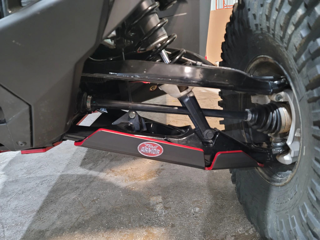 Trail Armor iMpact front arm guard installed on a Polaris RZR Pro R lower A-arm, side view with red edge trim