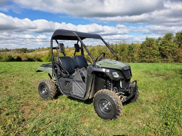 3 Star black soft top installed on a green Honda Pioneer 500, front three-quarter view in a sunny field