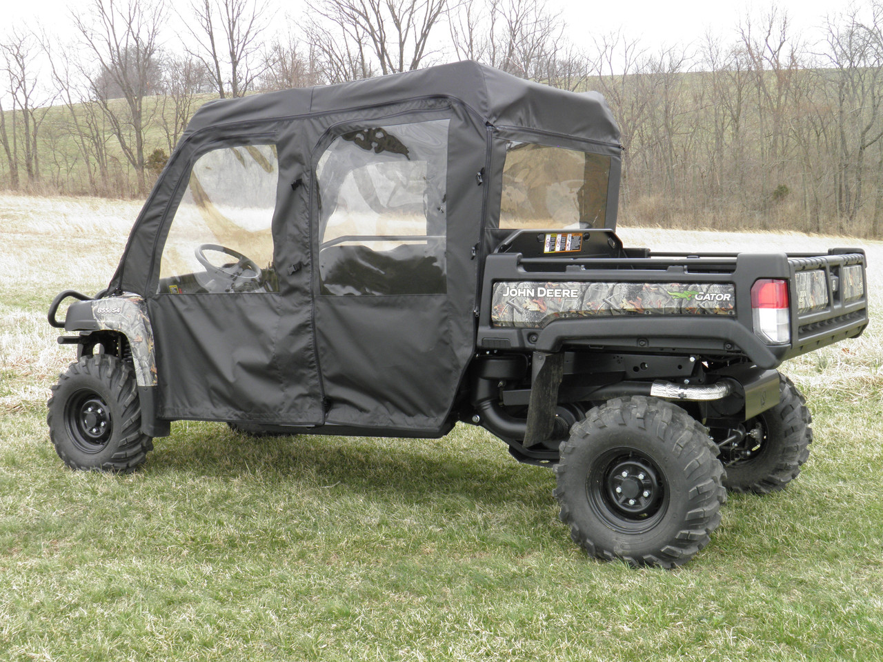 3 Star full cab enclosure with vinyl windshield on a camo John Deere Gator 4-seater, side view on frosty grass