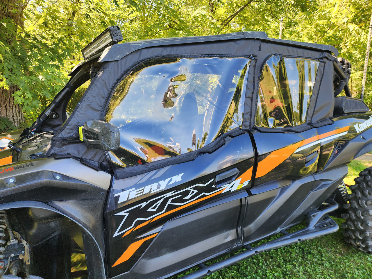 Front three-quarter view of the Kawasaki Teryx KRX Crew with the 3 Star upper doors installed under trees