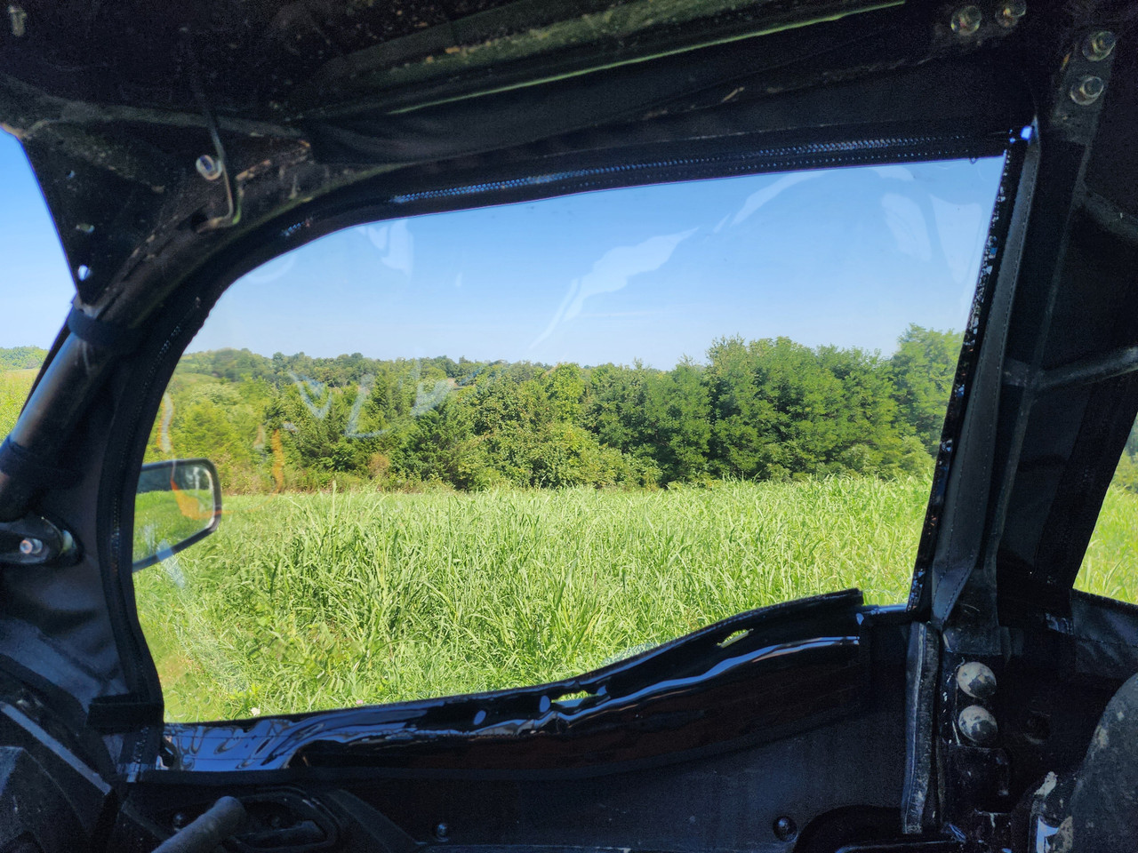 Inside view through the 3 Star upper door window on a Kawasaki Teryx KRX Crew, mirror and field beyond
