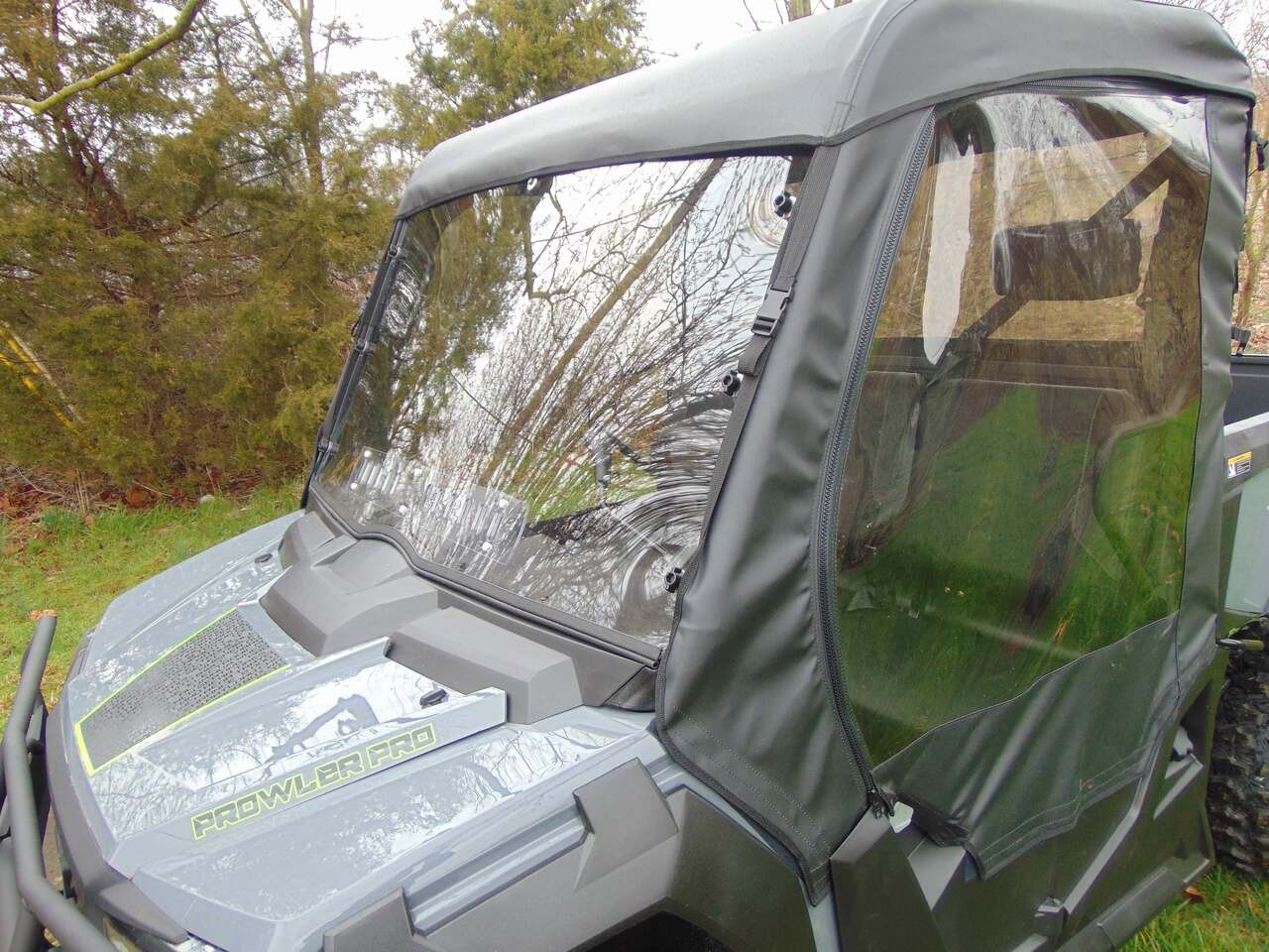 Front corner close-up of the 3 Star cab enclosure doors and hard windshield on a gray side-by-side
