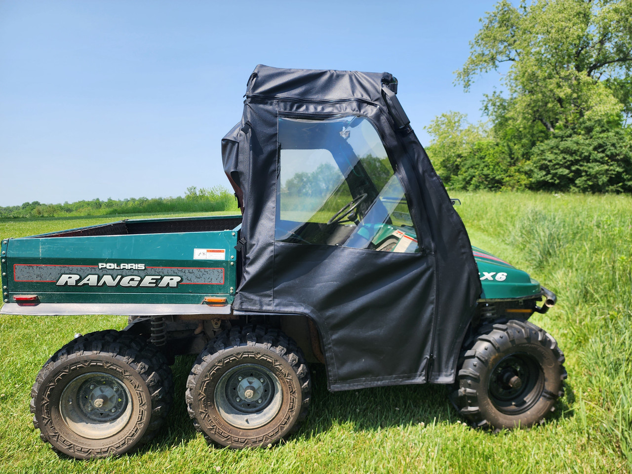 3 Star full cab enclosure with soft doors installed on a green 1999 Polaris Ranger 6x6, driver side view
