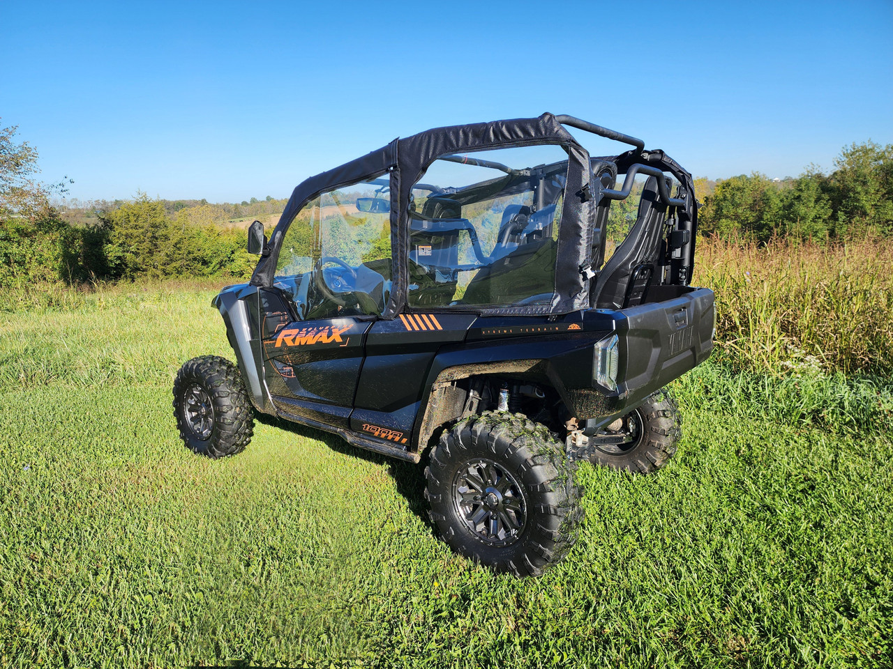 Front corner view of a blue Yamaha Wolverine RMAX 4-1000 with the 3 Star upper doors in tall grass