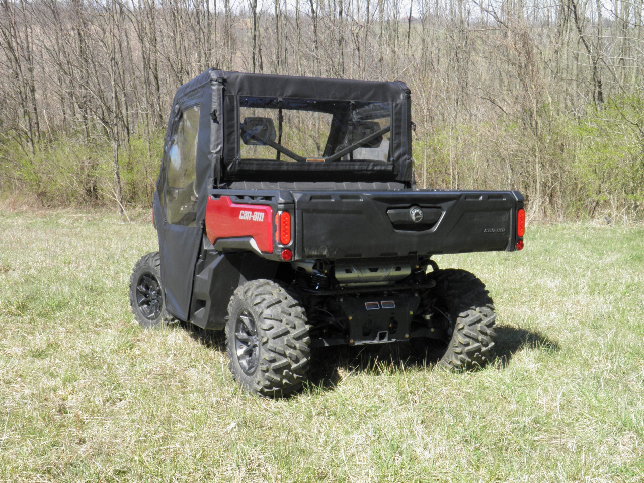 3 Star door and rear window combo on a red Can-Am Defender, rear three-quarter view over the bed in a field