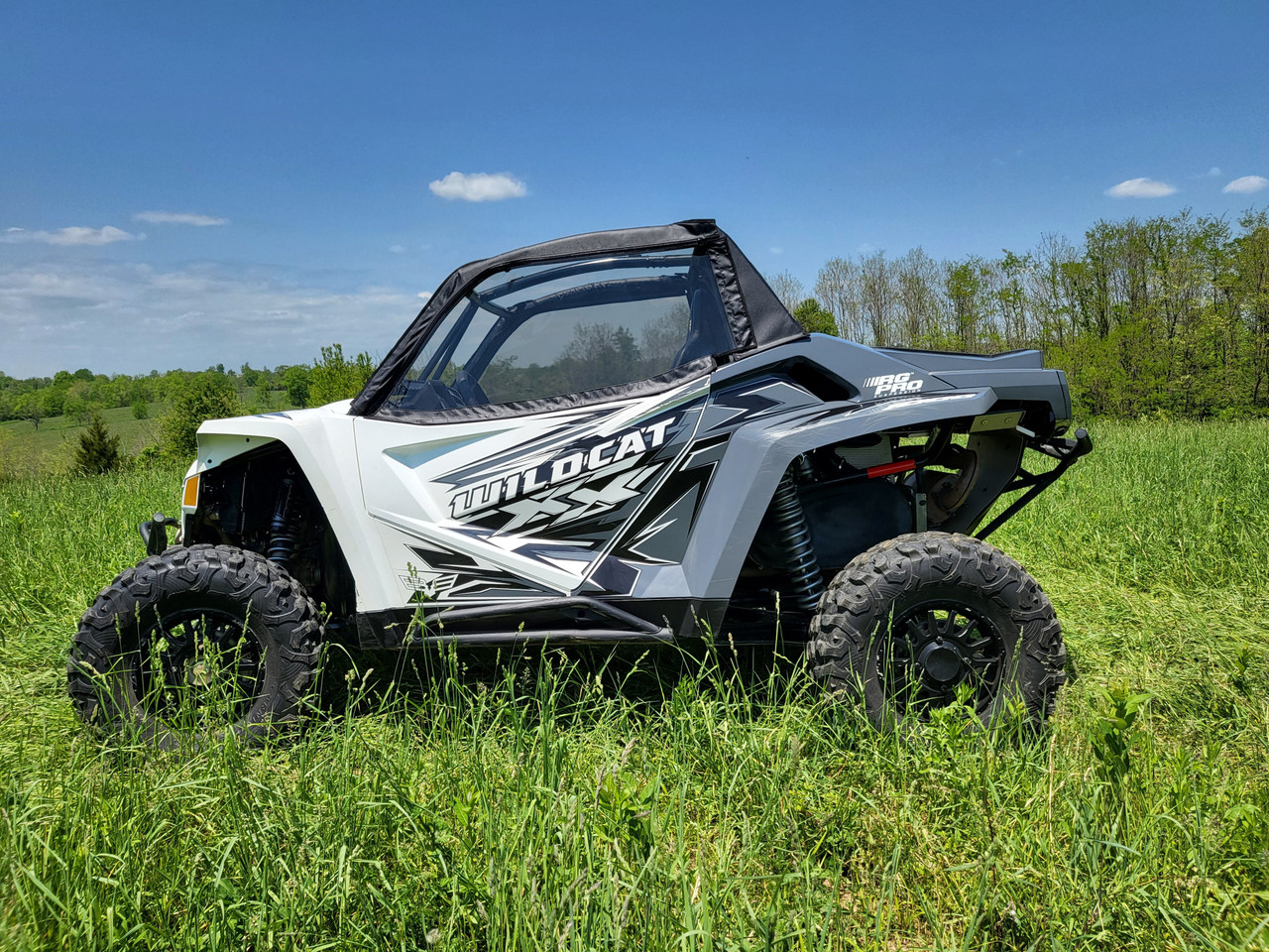 Front three-quarter view of a white Arctic Cat Wildcat XX with the 3 Star upper doors installed in tall grass