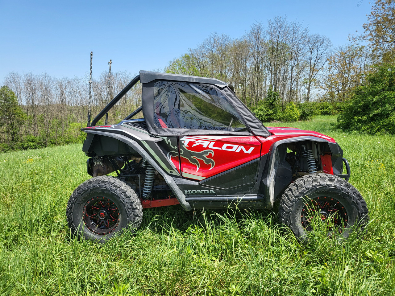 Driver side profile of the red Honda Talon 2-seater with 3 Star upper doors and rear panel in tall grass