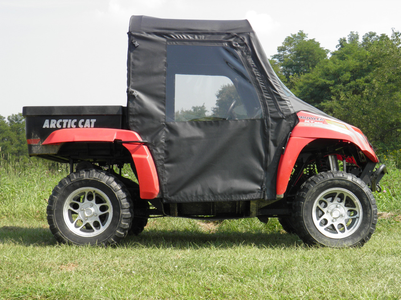 Driver side profile of the red Arctic Cat Prowler with 3 Star soft doors zipped shut on grass